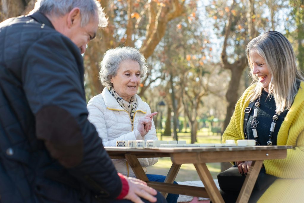 senior friends playing game outside around table