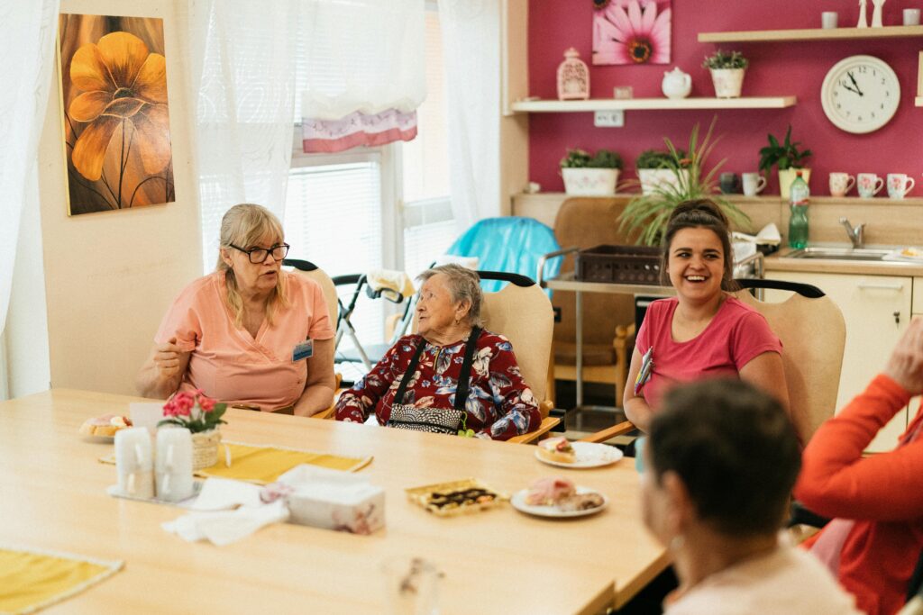 seniors with staff members sitting at table smiling