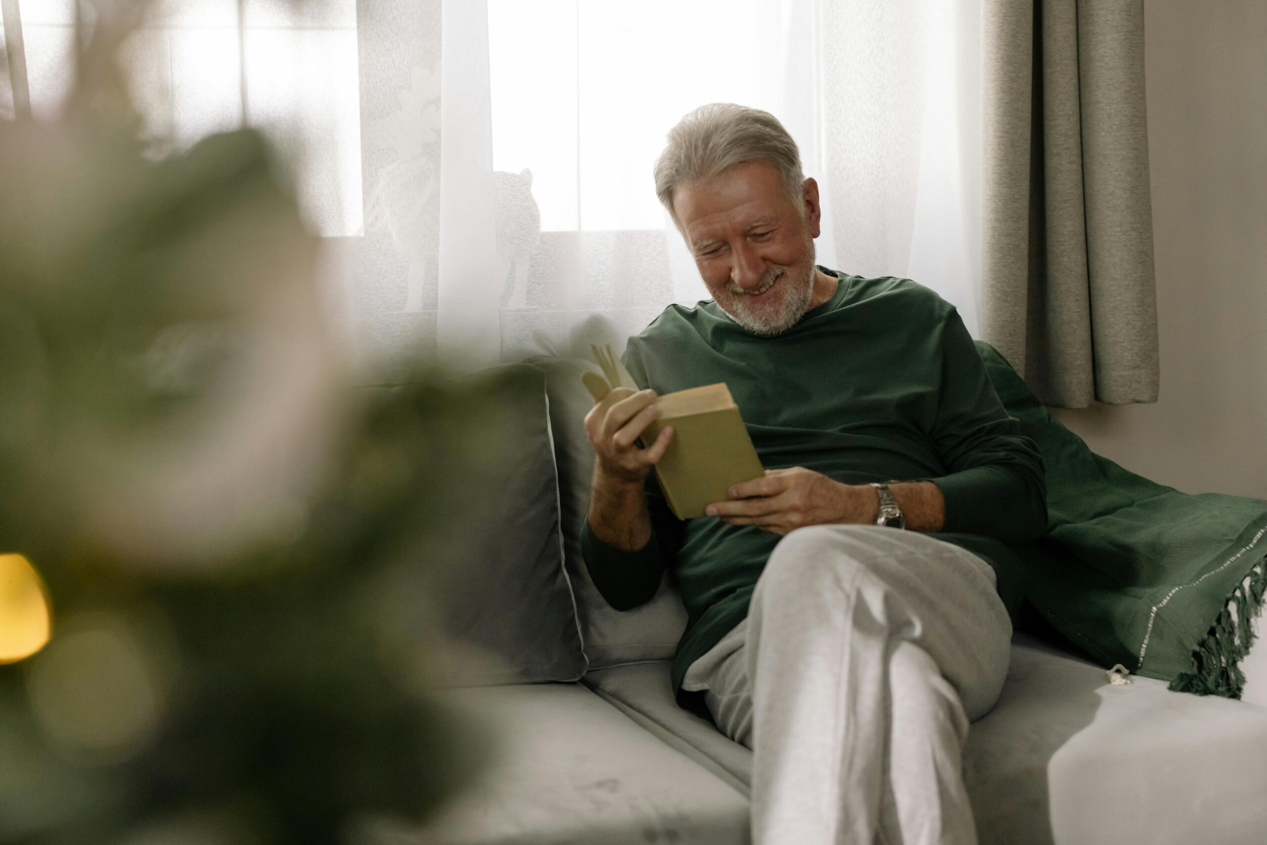 senior man happily reading on a couch